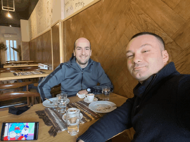 two men sit at a table in a restaurant with a sign on the wall that says " dont be a potato "