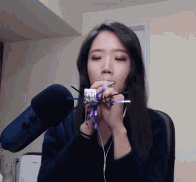 a woman blows a party horn in front of a blue microphone
