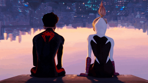 a man and a woman are sitting on a ledge looking at the city