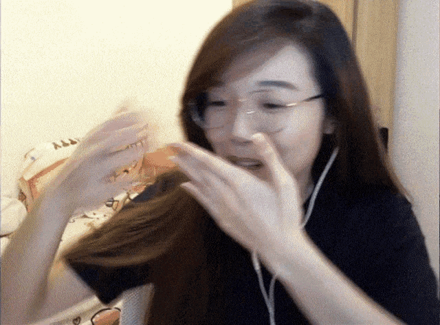 a woman wearing glasses and headphones holds her hands to her mouth