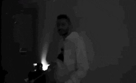 a black and white photo of a man in a white hoodie standing in a room .