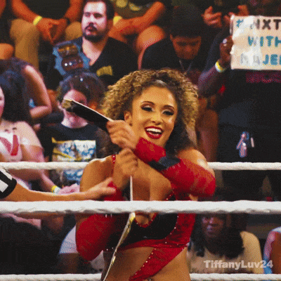 a woman in a wrestling ring holding a sign that says #next vs. major