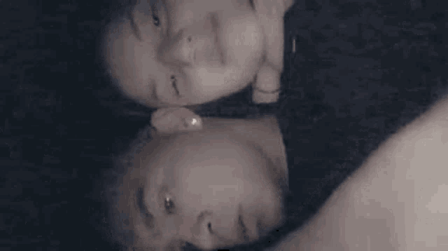a man and a woman are laying next to each other on a bed and looking at each other .