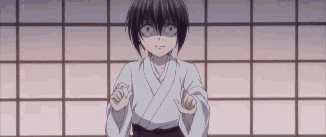 a young boy in a white kimono is making a funny face while standing in front of a window .