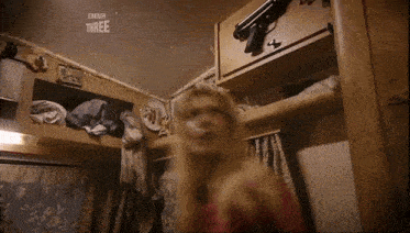 a woman is standing in a room with a bbc three logo on the wall