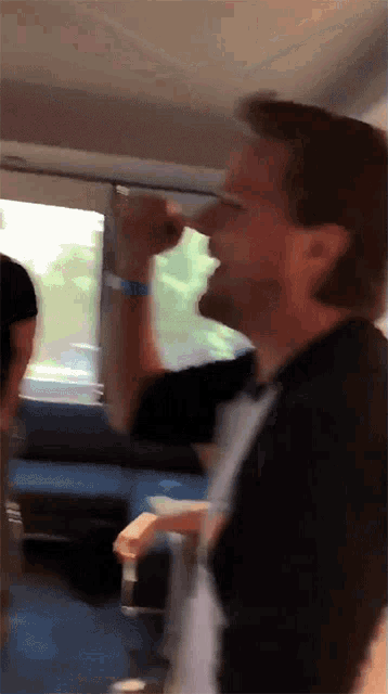 a man in a black shirt is drinking from a bottle