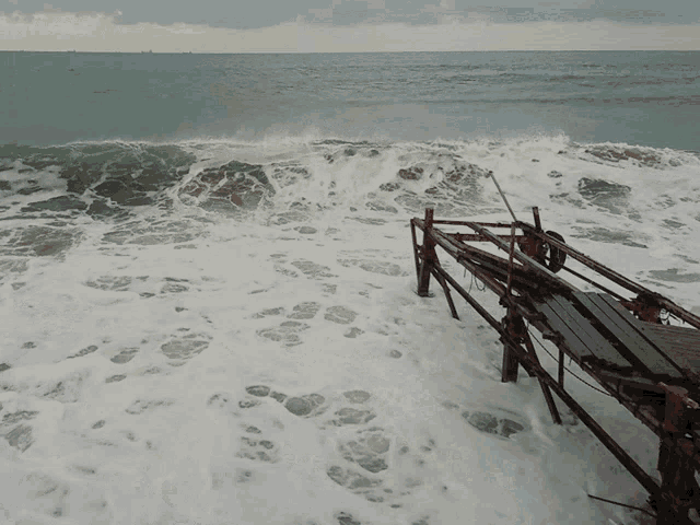 waves crashing against a wooden structure on the shore