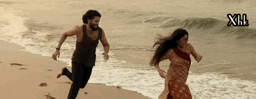a man and a woman are running on a beach with xnr written in the corner