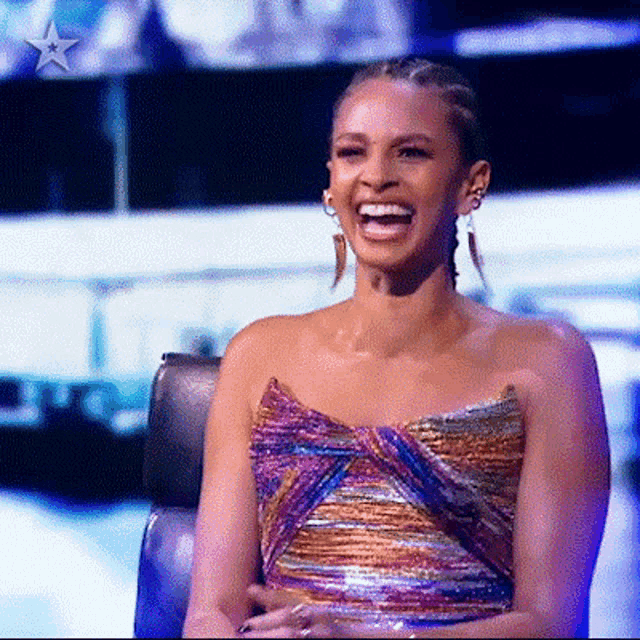 a woman in a colorful dress is sitting in a chair laughing