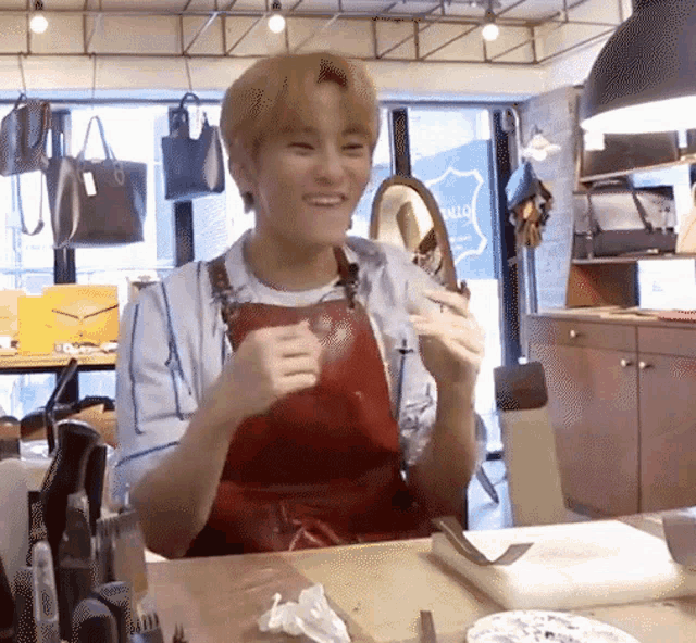 a man wearing an apron is sitting at a table with a plate of food