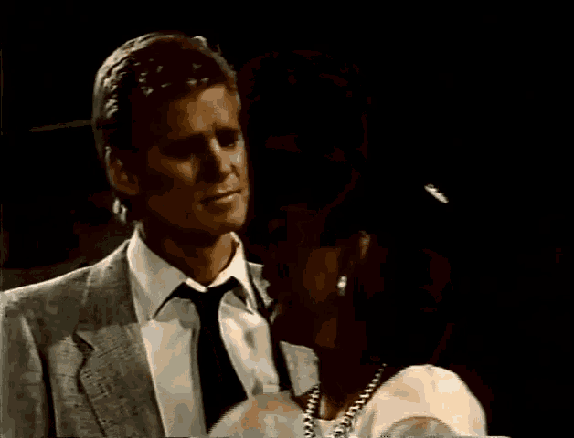 a man in a suit is hugging a woman in a white dress