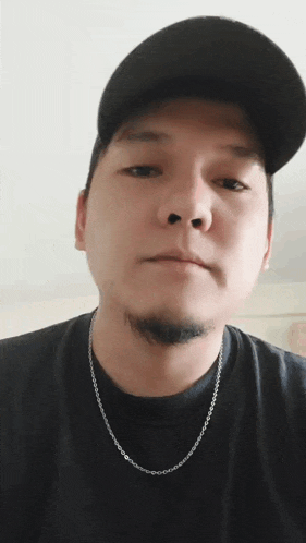 a man wearing a black hat and a silver chain