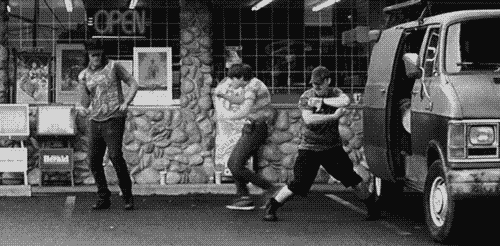 a group of young men are dancing in front of a van in a parking lot .