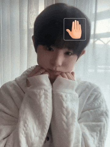 a person wearing a white sweater has their hands on their chin