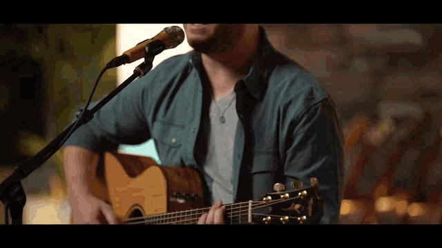 a man is singing into a microphone while playing a guitar