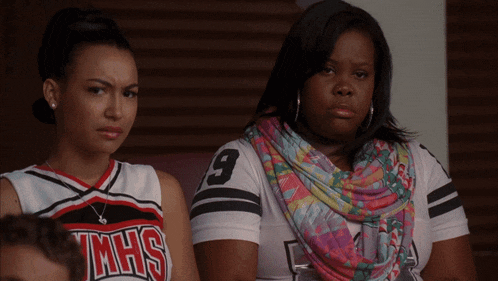 a cheerleader wearing a jmhs shirt sits next to another cheerleader