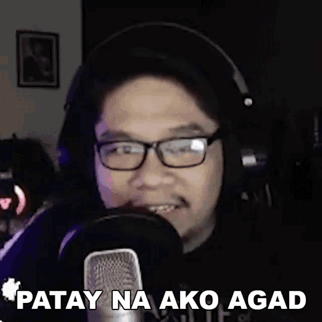a man wearing glasses and headphones is talking into a microphone and making a funny face .