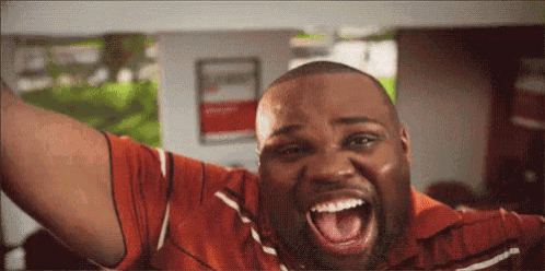 a man in a red shirt is screaming with his mouth open .