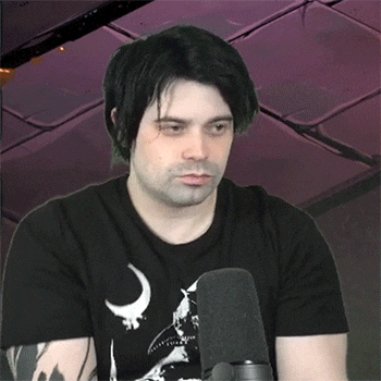 a man wearing a black shirt with a crescent moon on it is standing in front of a microphone