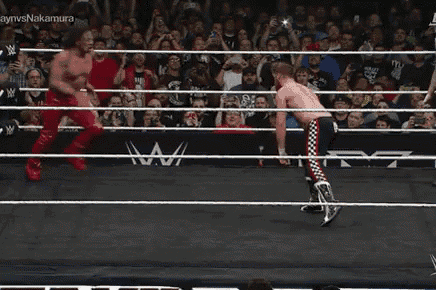 two men are wrestling in a ring and one is doing a handstand .