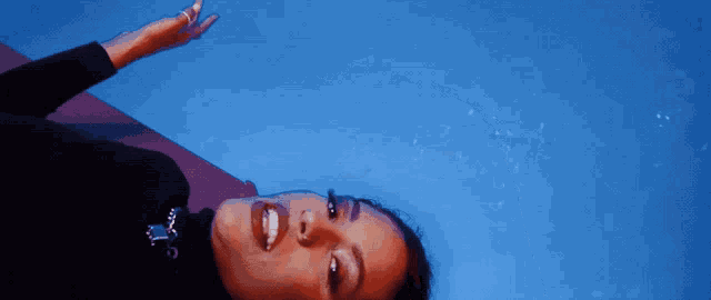 a woman in a black turtleneck is laying on her back and smiling
