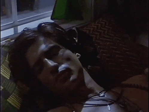 a man laying on a couch with his eyes closed and a necklace around his neck