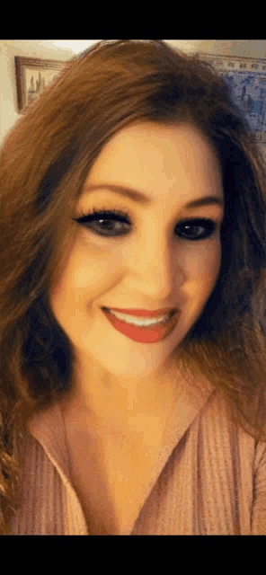 a woman wearing a pink shirt and red lipstick smiles for the camera