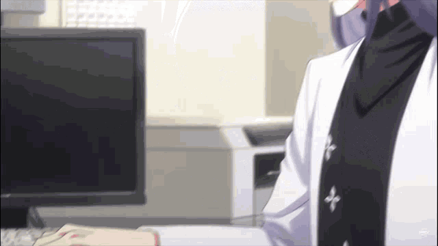 a man in a lab coat is sitting in front of a computer monitor .