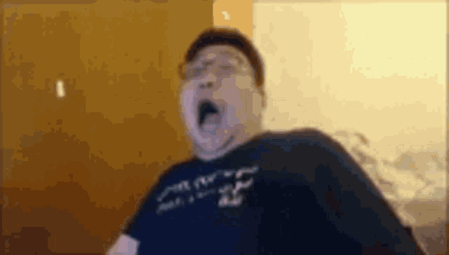 a man with glasses is yawning while wearing a black shirt with the number 25 on it .