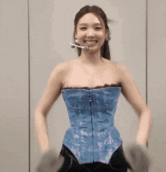 a woman wearing a blue corset and a microphone is smiling .