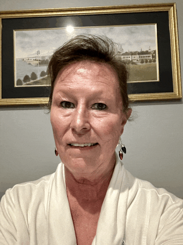 a woman is smiling in front of a framed picture of a bridge