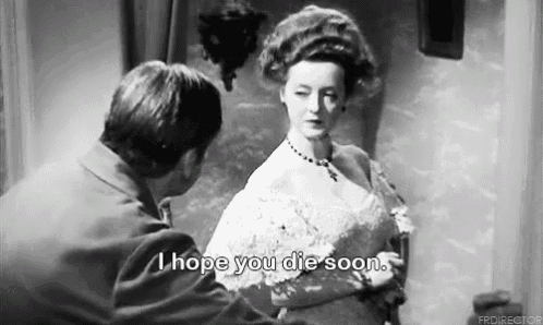 a black and white photo of a man and a woman talking to each other . the woman is wearing a white dress .