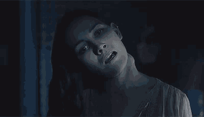 a woman is standing in a dark room with her head up and her mouth open .