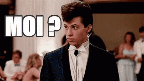 a man in a tuxedo is standing in front of a sign that says moi .