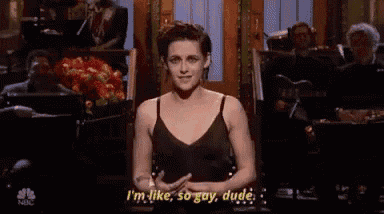 a woman in a black tank top is standing in front of a crowd and saying i 'm like so gay dude