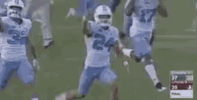 a football player in a blue jersey with the number 24 on it is running on a track .