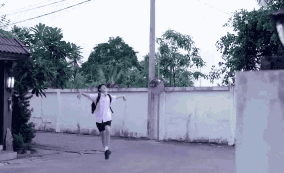 a boy in a school uniform is jumping in the air with his arms outstretched