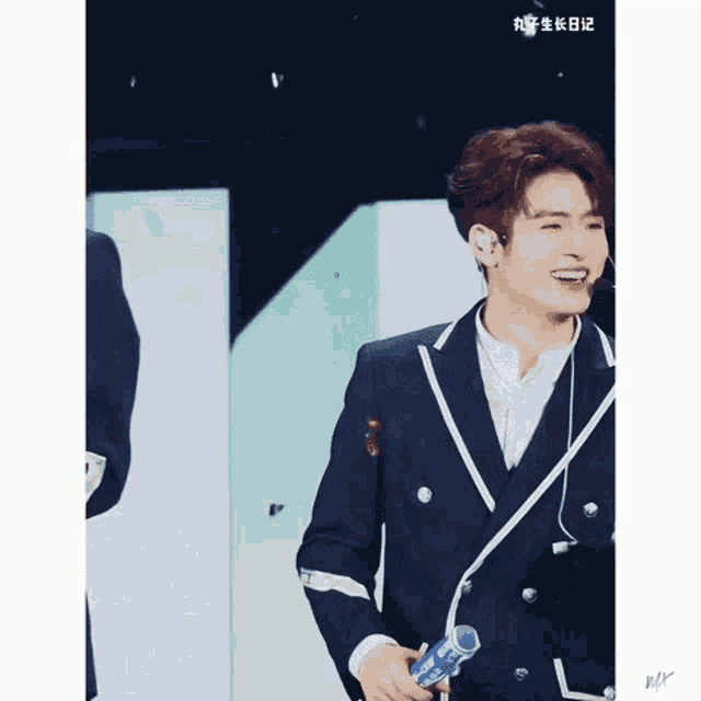 a young man in a suit is holding a microphone and smiling .