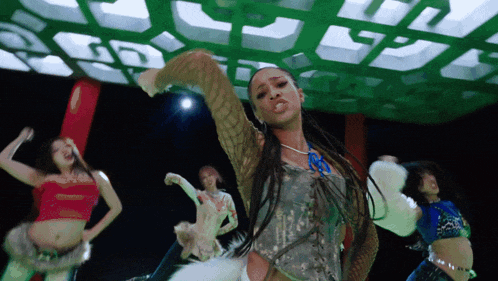 a group of women are dancing in front of a green light