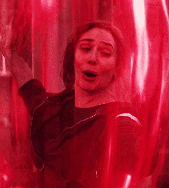 a woman is behind a red curtain with a red light coming out of it