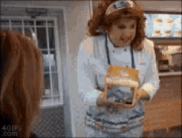 a woman is holding a box of cereal in her hand