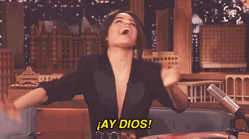 a woman is sitting in front of a microphone with her arms outstretched and says ay dios .