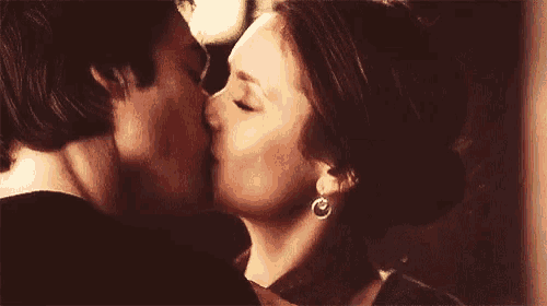 a man and a woman are kissing in front of a wall .