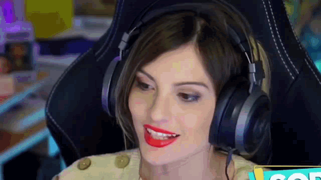a woman wearing headphones and red lipstick is sitting in a gaming chair .