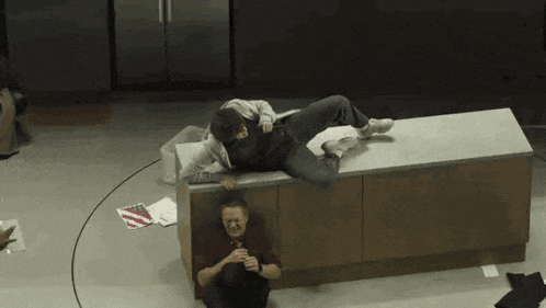 a man and a woman are sitting on a counter in a kitchen . the woman is wearing a mask .