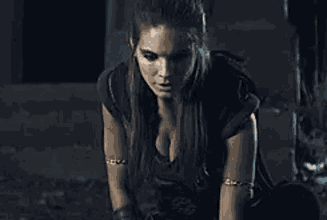 a woman is sitting on the floor in a dark room with her breasts visible .