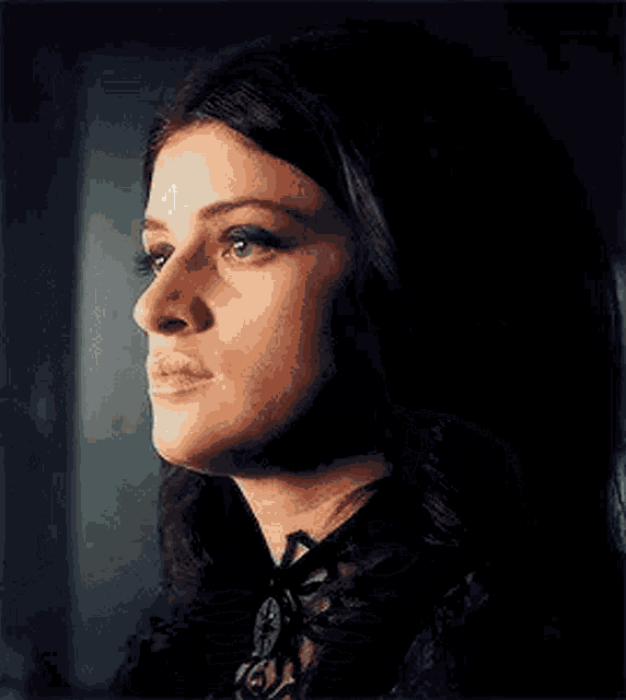 a woman is looking out of a window and smoking a cigarette in a dark room .