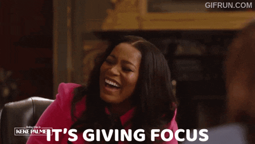 a woman in a pink jacket says it 's giving focus while sitting in a chair