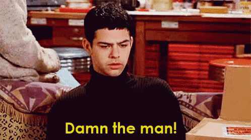 a man in a black turtleneck sweater is sitting on a couch and says damn the man
