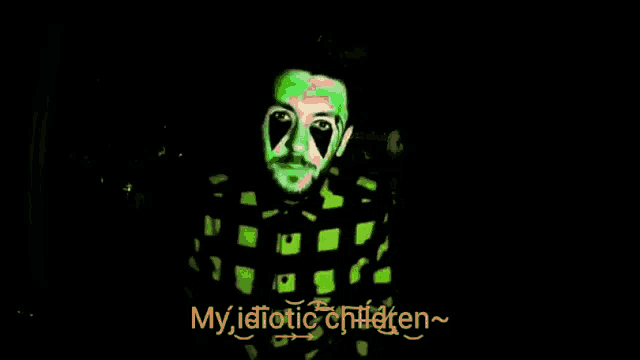 a man in a green plaid shirt is smiling in the dark with the words my idiotic children below him